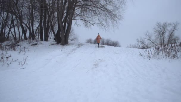 Bambino felice rotola con la collina di neve in inverno . — Video Stock