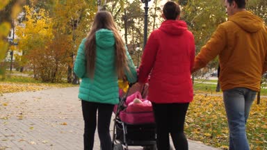 Bebek Puseti içinde anne-babası ve kız kardeşi ile yolda park biniyor. Ağır çekim.