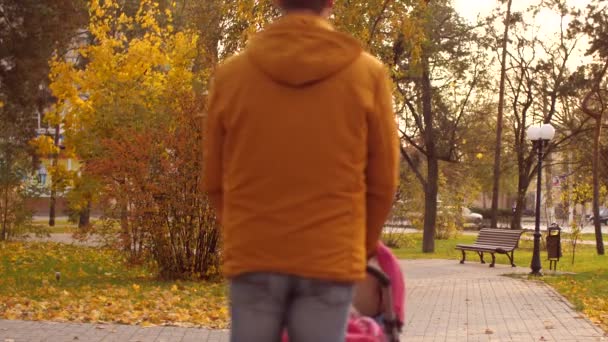 Homme marche avec poussette dans le parc d'automne. Mouvement lent .