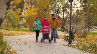 Bebek Puseti içinde anne-babası ve kız kardeşi ile yolda park biniyor. Ağır çekim.
