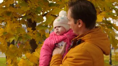 Bebek ve baba dokunmatik altın, sonbahar yaprakları ve gülümseme.