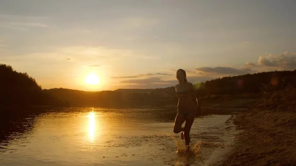 Adolescente chica corre a lo largo de la playa al atardecer . — Foto de Stock