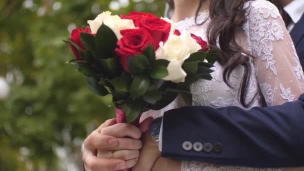 男は、花嫁の手の中の色とりどりのバラの花束を抱いて白いドレスに花を持つ少女 — ストック動画