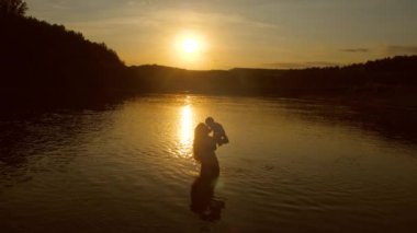 Bebek mi anne, kollarında günbatımında suya düştü. Ağır çekim.