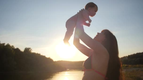 Bebek ve anne günbatımı kırmızı güneşe birlikte. Ağır çekim. — Stok video