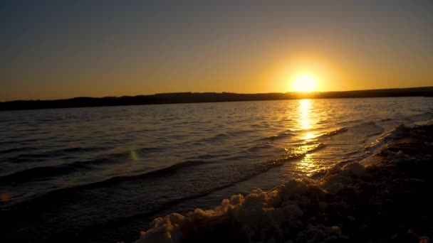 Golven op water en schuim tegen zonsondergang. Slow motion. — Stockvideo