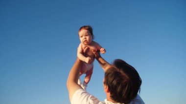 mutlu bebek mavi gökyüzünde baba eller tarafından ağır çekim kaldırdı.
