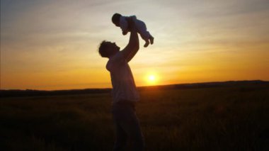 Bebek babasının altın güneş batımında ellerinizde. Ağır çekim.