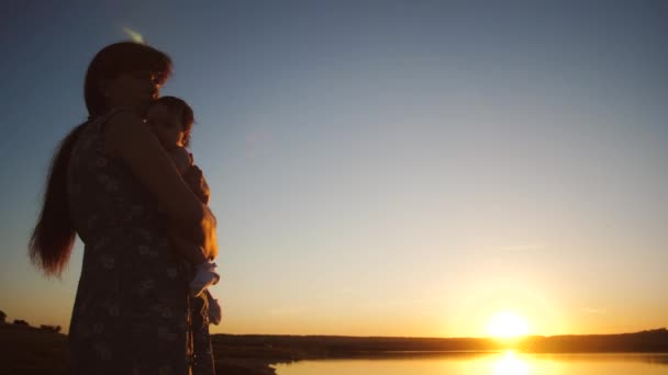 Le bébé est dans les bras de la mère au coucher du soleil soleil doré. Mouvement lent . — Video