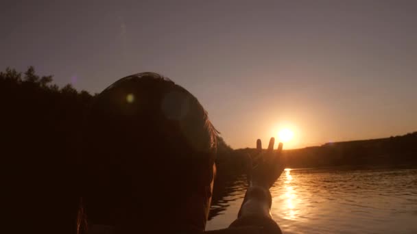 Young girl extends her hand to sunset over the river — Stock Video