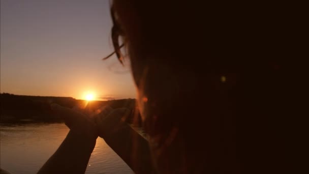 Девушка держится в ладонях солнца на фоне неба — стоковое видео