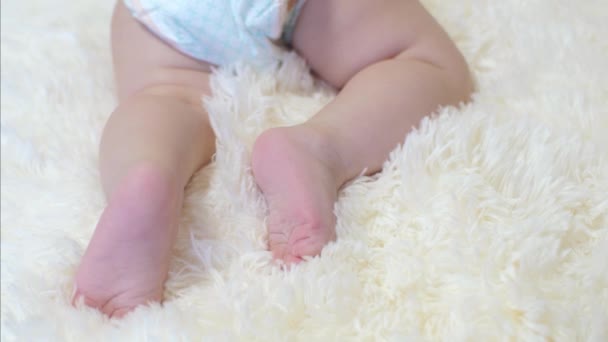 Bebé en pañal mueve sus piernas acostado . — Vídeo de stock
