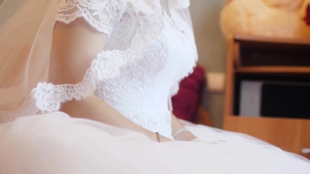 Bride in beautiful white dress sits and looks out the window — Stock Video