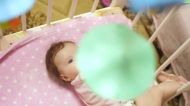 Bebek beşik oyuncaklar ile yatıyor ve onun tarafında çevirir. Ağır çekim,