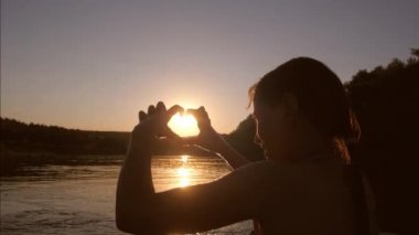 nehir genç kız kalp şekli ile el günbatımında gösterir.