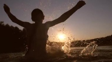 Kız gün batımında suda yıkıyor