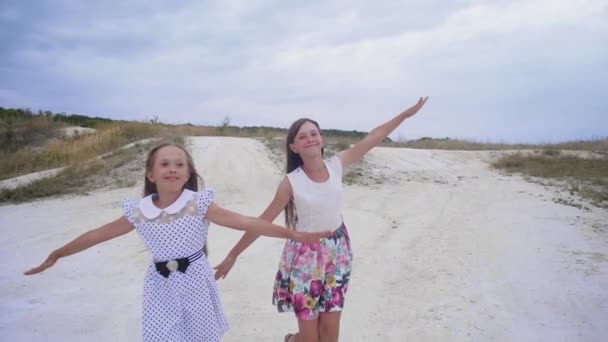 Flickor tonåringar löper längs vägen sprida sina armar som vingar. Slow motion. — Stockvideo