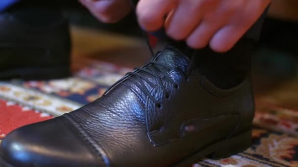 Człowieka wiąże się jego sznurowadła na jego czarne buty — Wideo stockowe
