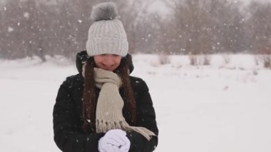 Güzel kız gülümseyerek ve ileri atma beyaz saf kar kartopu yapma.