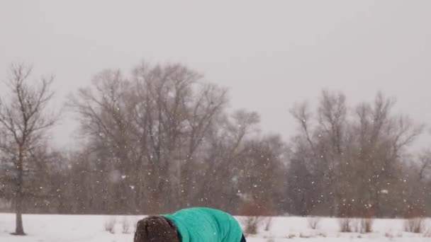 Blij en zorgeloos vrouw spelen sneeuwballen in het sneeuw Park. Er is sterke sneeuwstorm. — Stockvideo