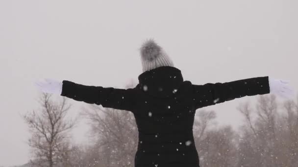 Menina feliz pega flocos de neve olhando para o céu e sorri . — Vídeo de Stock