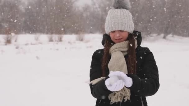 Vacker flicka gör av snö snöboll. — Stockvideo