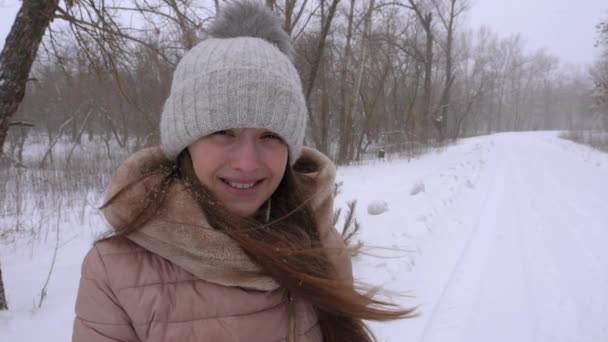 Όμορφο κορίτσι χαμογελά σε ισχυρή χιονοθύελλα, το χειμώνα. Αργή κίνηση. — Αρχείο Βίντεο