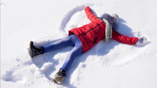 Un niño feliz hace un ángel de nieve. Moción lenta . — Vídeo de stock