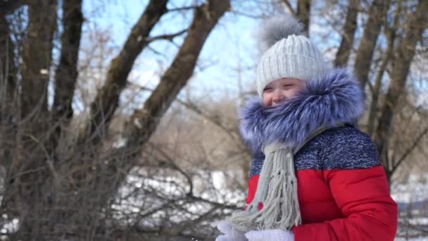 Child playing in park in snowballs.Portrait of a baby girl outside in winter. Slow Motion. — Stock Video