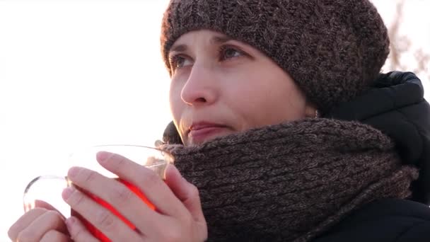 Belle fille congelée buvant du thé à partir de verre transparent en plein air . — Video