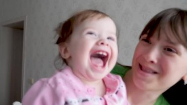 Bebek anne kucağında gülüyor ve çalış. İlk süt dişleri. Ağır çekim.