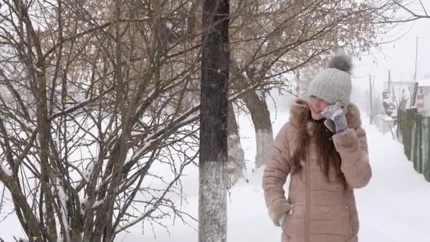 Ragazza che parla al telefono Camminando su strada innevata, tempesta di neve, in inverno. Rallentatore . — Video Stock