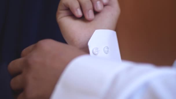 Man fastens buttons on tsleeve of white shirt — Stock Video