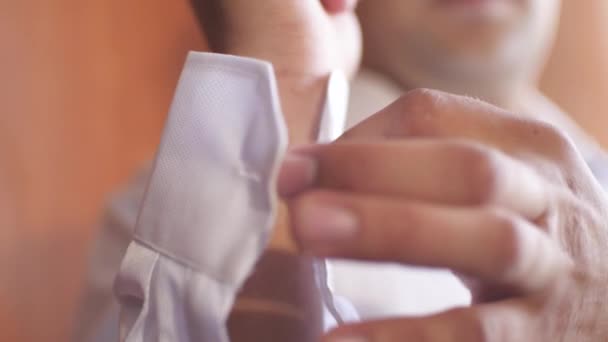 Man fastens buttons on tsleeve of shirt, man wears turquoise shirt — Stock Video