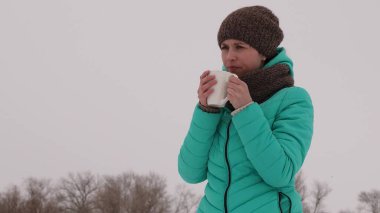 Donmuş kız kendini kışın soğuk temiz havada sıcak kupa ile ısıtıyor. Kış Park çay iç. Sıcak kahve.