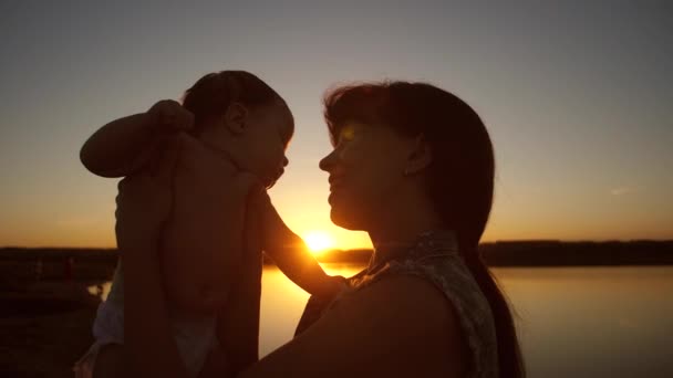 Moeder praat met de baby bij zonsondergang van de gouden zon. Slow motion. — Stockvideo