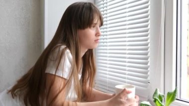 Genç kız üzerinde pencere pervazına pencere yakınındaki çay içecekler.