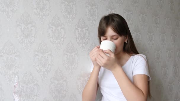 Teenager-Mädchen beginnen den Tag mit einer Tasse heißem Tee im Zimmer. — Stockvideo