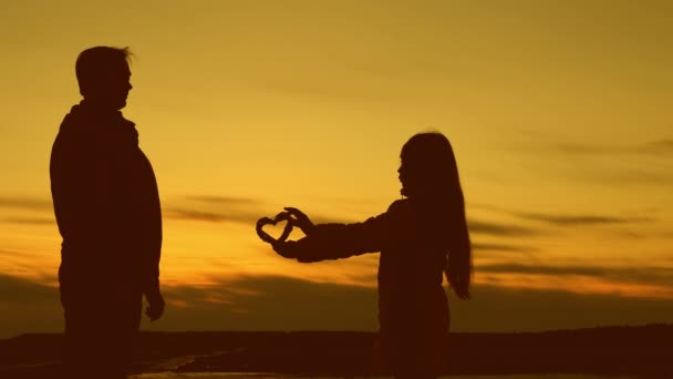 Little child gives in heart to his dad at sunset. — Stock Video