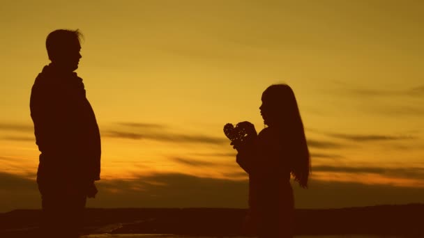 Liefdevolle vader met dochter, hart in hun handen houden, rouwen bij zonsondergang van zon. — Stockvideo