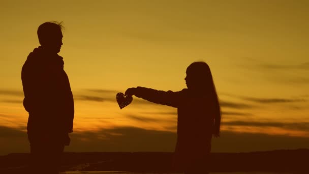 Flickan ger sitt hjärta att man vid solnedgången. — Stockvideo