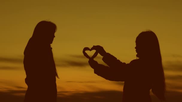 Las novias comparten el corazón unas con otras al atardecer del sol dorado . — Vídeo de stock