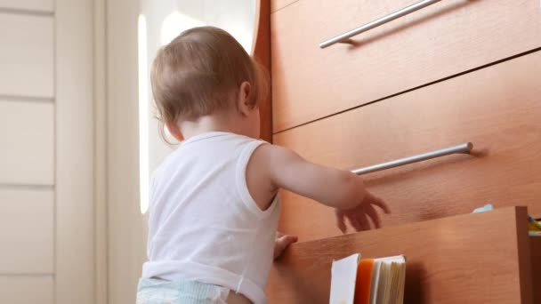 Liten bebis tar böcker ut ur garderoben. — Stockvideo