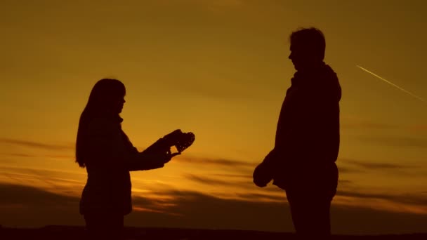 Menina dá seu coração ao homem ao pôr do sol . — Vídeo de Stock