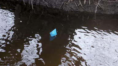 Nehir kıyısında renkli kağıt mavi kağıt tekne yüzen.