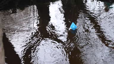 Mesafe içine acele nehir akarsu boyunca küçük renkli kağıt tekneler yüzmek.