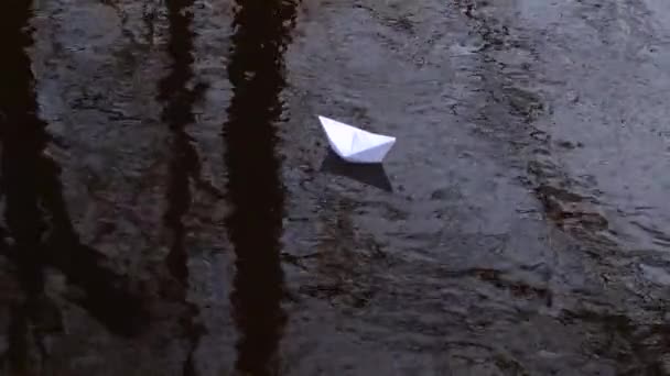 Barco de papel blanco que se refleja en el agua lleva corriente hacia adelante . — Vídeo de stock