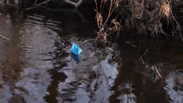 Barca di carta blu di carta colorata galleggia lungo la riva del fiume . — Video Stock