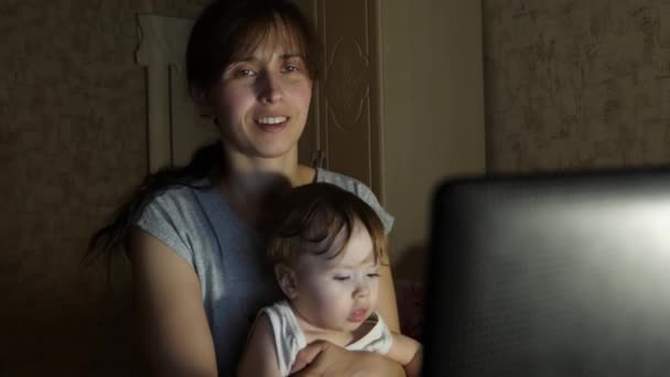 Επιχειρήσεων γυναίκα που εργάζονται στον υπολογιστή αργά τη νύχτα με ένα μωρό στην αγκαλιά της. — Αρχείο Βίντεο