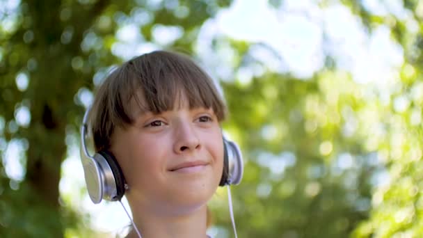 Girl in headphones listening to music in summer park — Stock Video